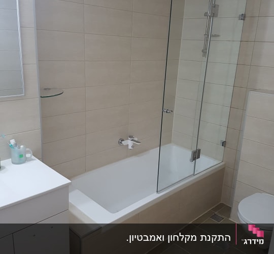 אמבטיון זכוכית שקופה מותקן על אמבטיה בחדר רחצה